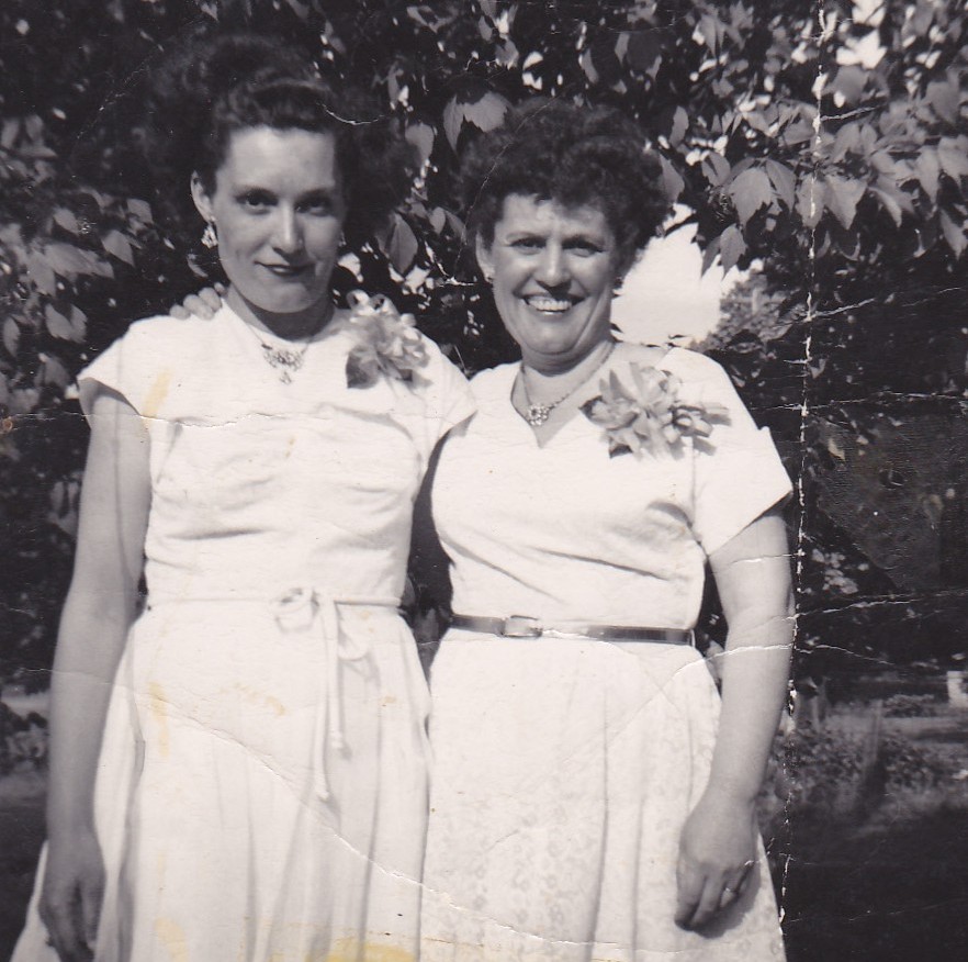Mary Doan and Mae Kain standing together in white dresses with corsages