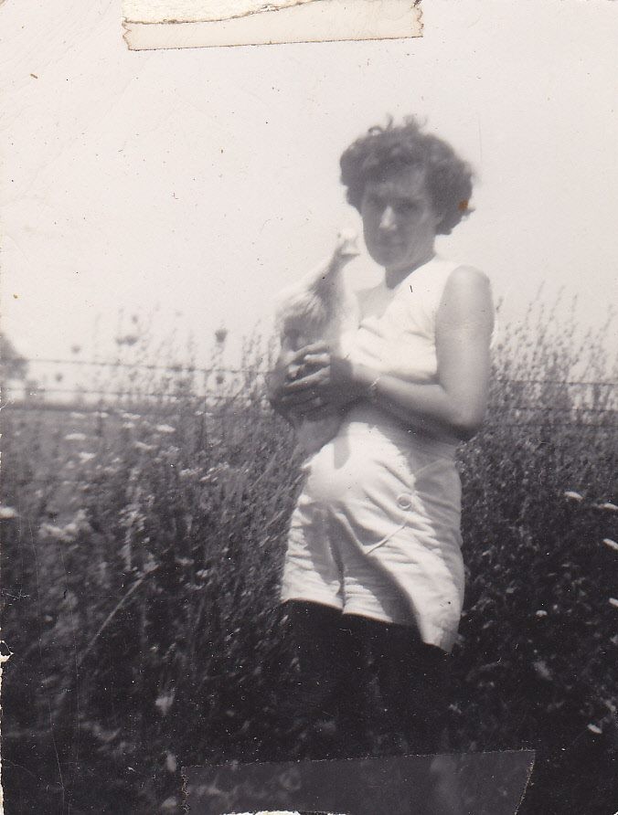 Mary Doan holding a duck in a field of tall grass and wildflowers
