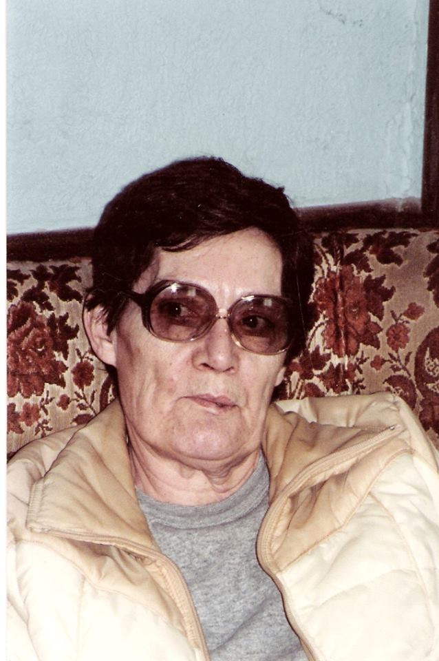 Mary Alice Doan wearing a cream vest, sitting on a floral couch