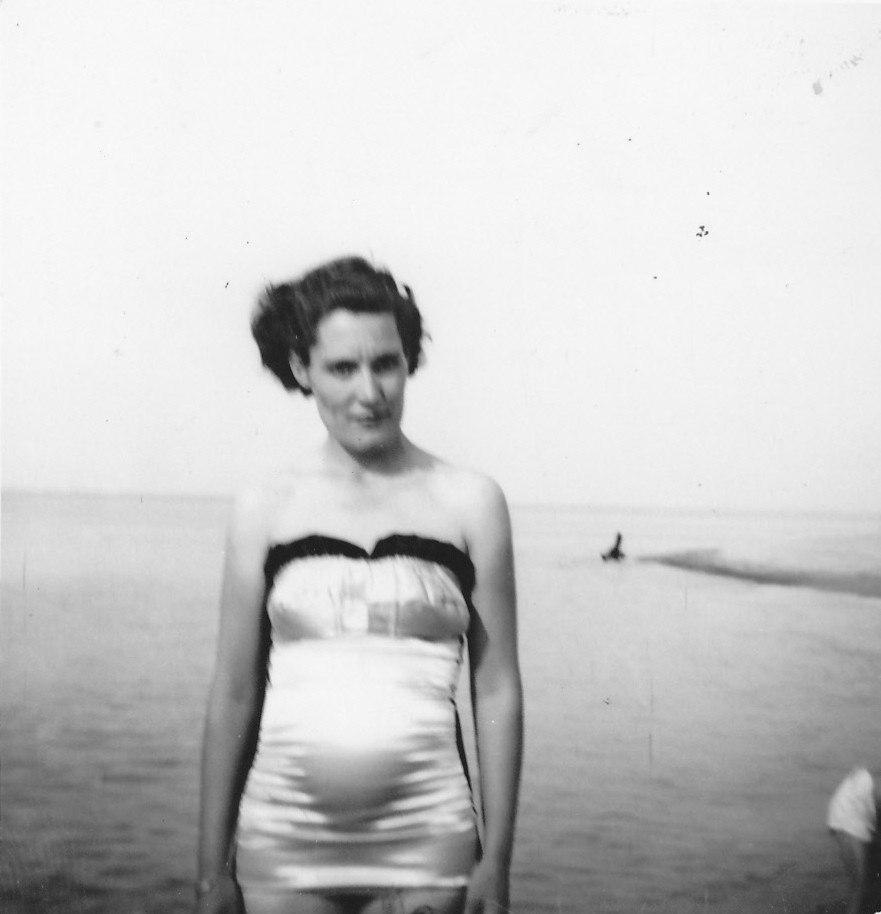 Mary Doan in a vintage bathing suit, standing by the lake