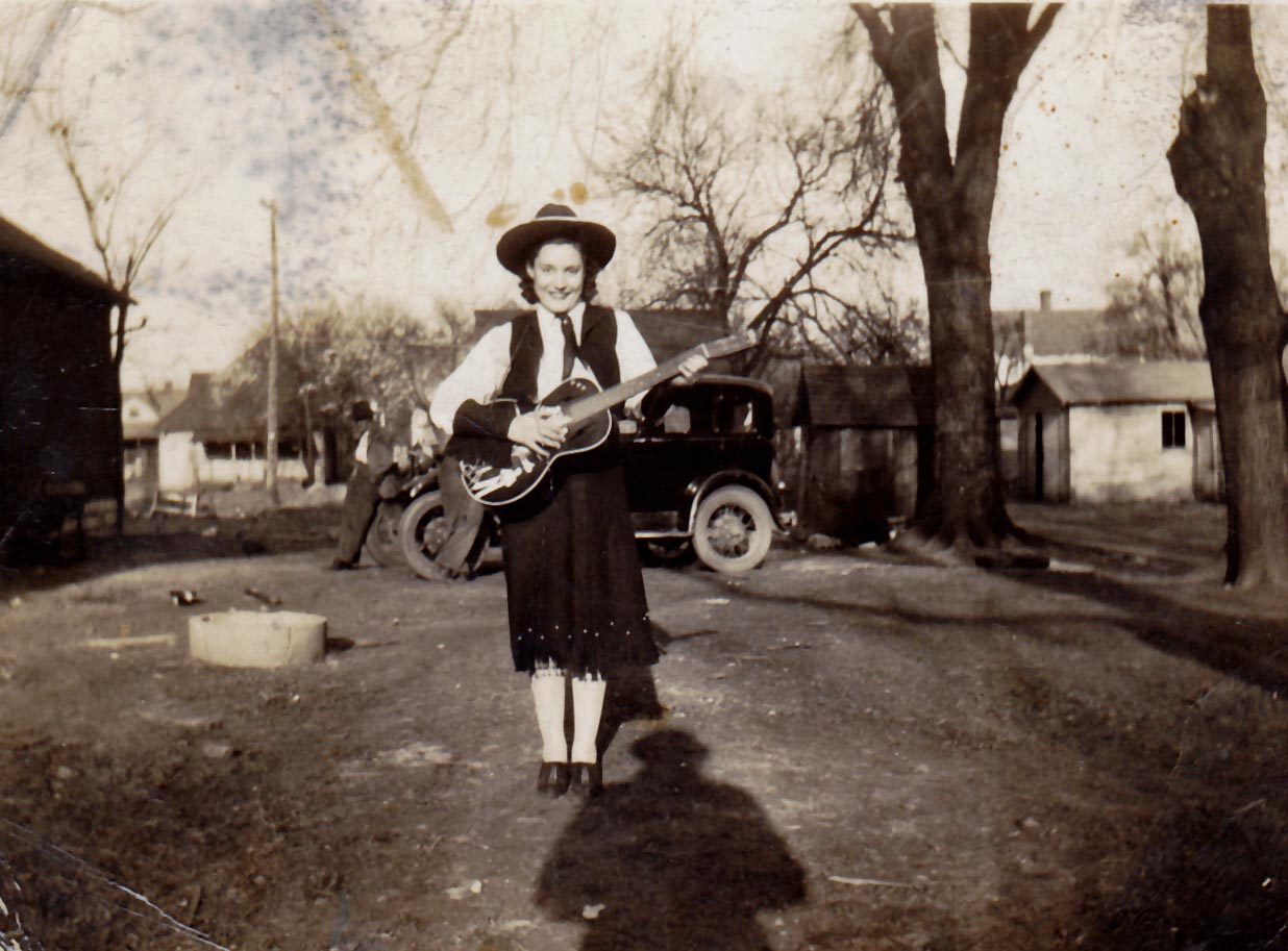 Mary Harris in cowgirl outfit with guitar