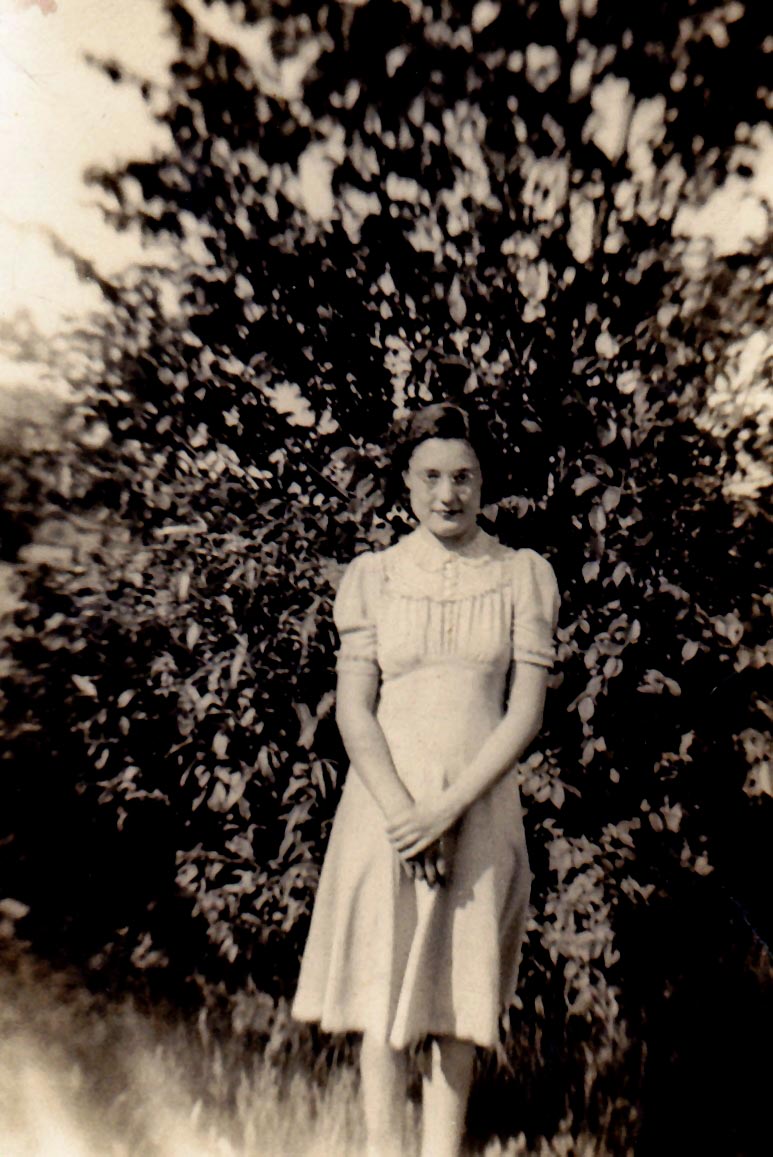 Young Mary Alice Harris standing in front of a leafy tree